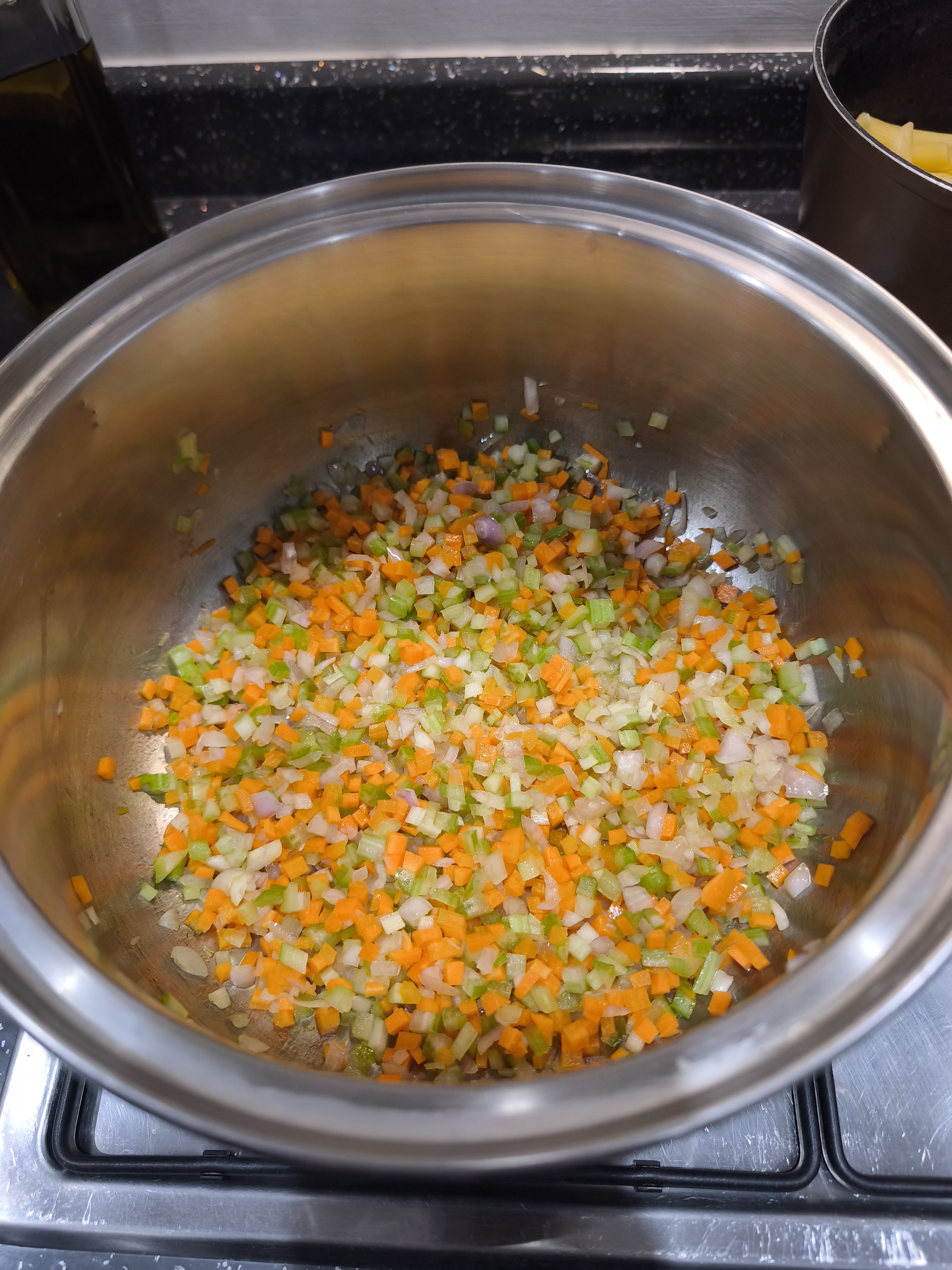 A mix of diced carrots, celery, and shallots in a pot.