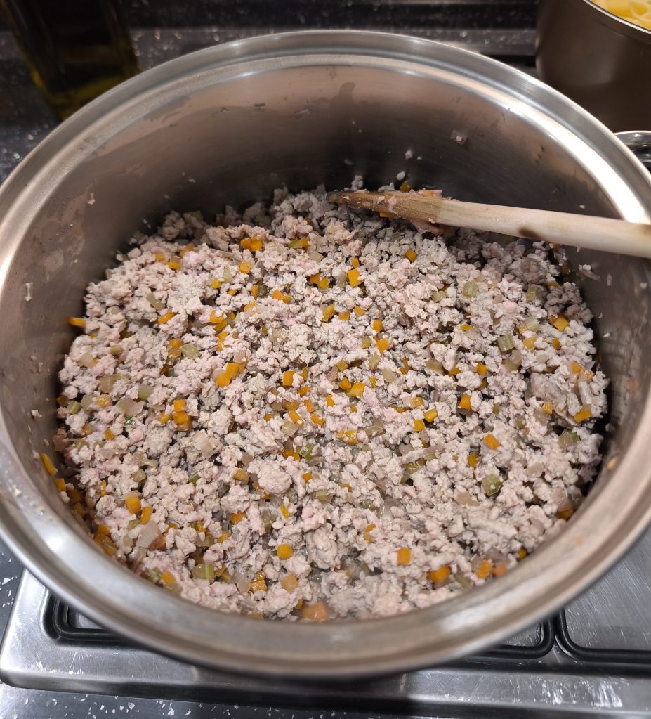 Cooked ground meat mixed with sautéed vegetables in a pot.